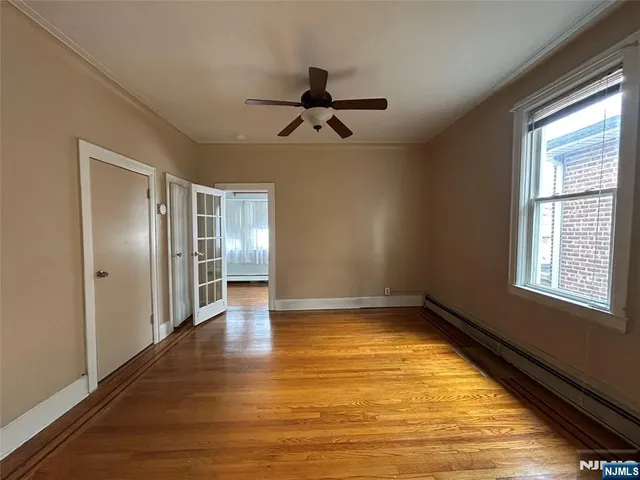 a view of empty room with wooden floor and fan