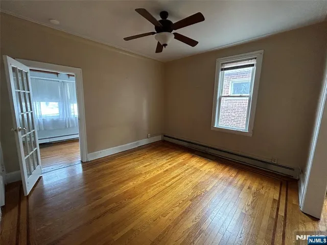 a view of empty room with wooden floor and fan