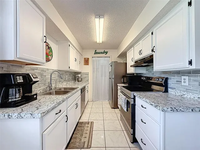 a kitchen with stainless steel appliances granite countertop a stove a sink and a microwave