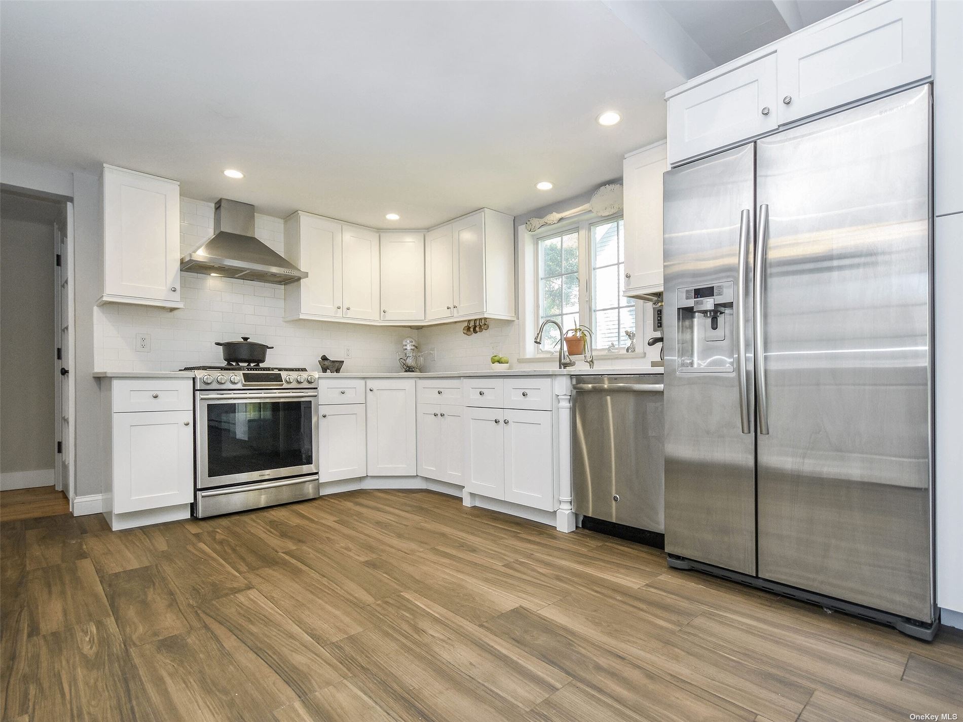 a kitchen with stainless steel appliances a refrigerator sink and white cabinets