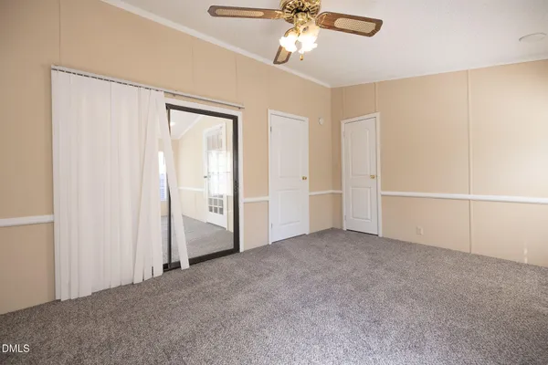 a view of an empty room and chandelier fan