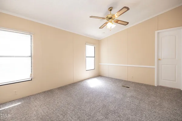 an empty room with windows and fan