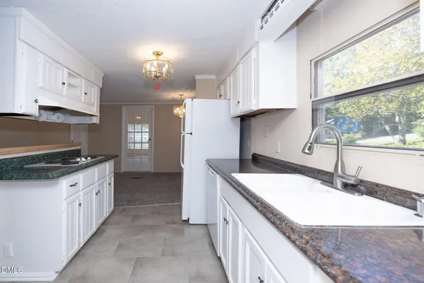a kitchen with granite countertop a sink a counter top space and cabinets