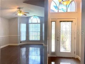 an empty room with wooden floor fan and windows