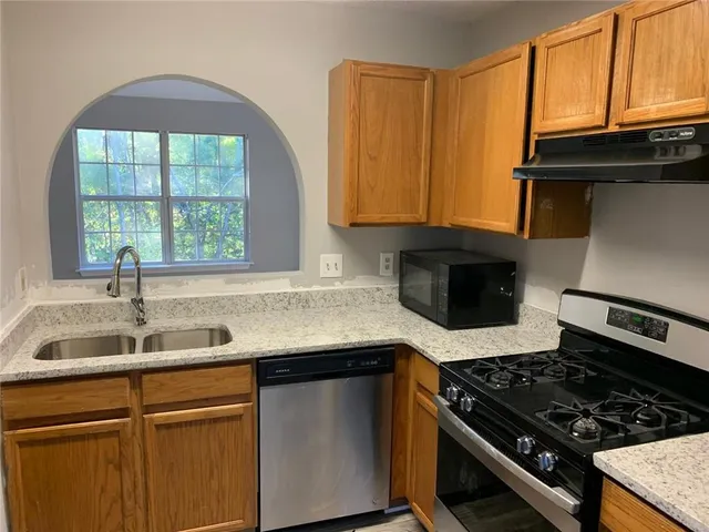 a kitchen with granite countertop a sink a stove and cabinets