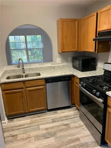 a kitchen with granite countertop a stove a sink and a microwave