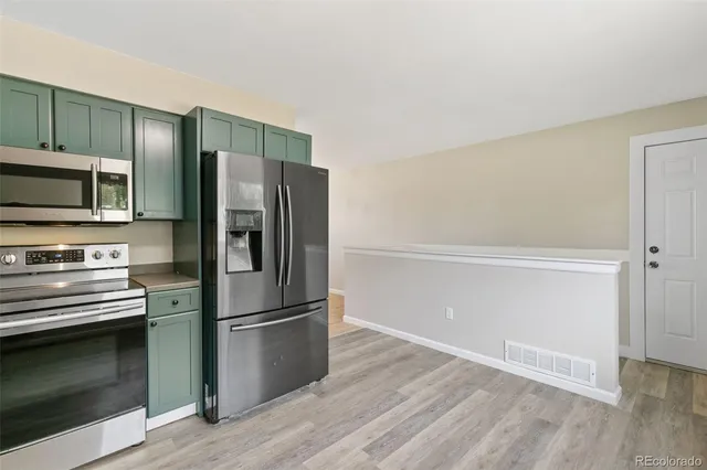 a kitchen with granite countertop a refrigerator stove and sink