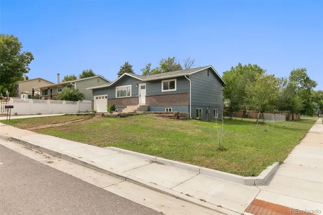 a view of house with yard outdoor seating and covered with trees
