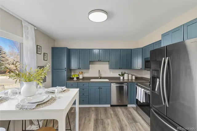 a kitchen with stainless steel appliances granite countertop a sink dishwasher stove top oven and refrigerator with wooden floor