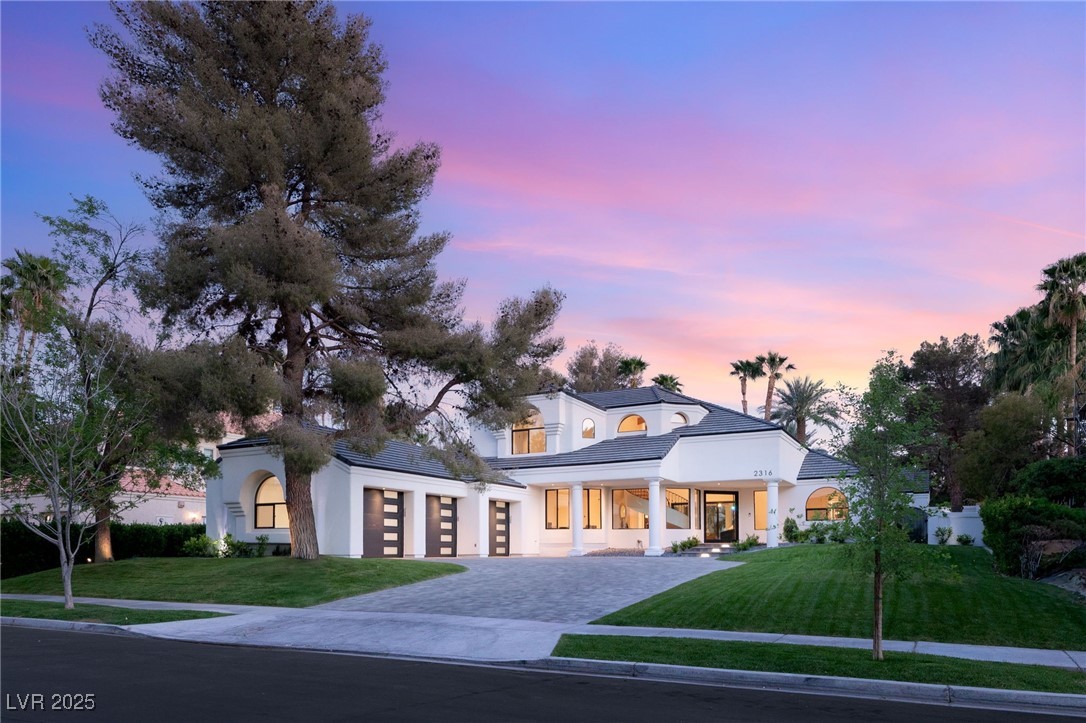 View of front of property with a yard, stucco siding, and decorative driveway