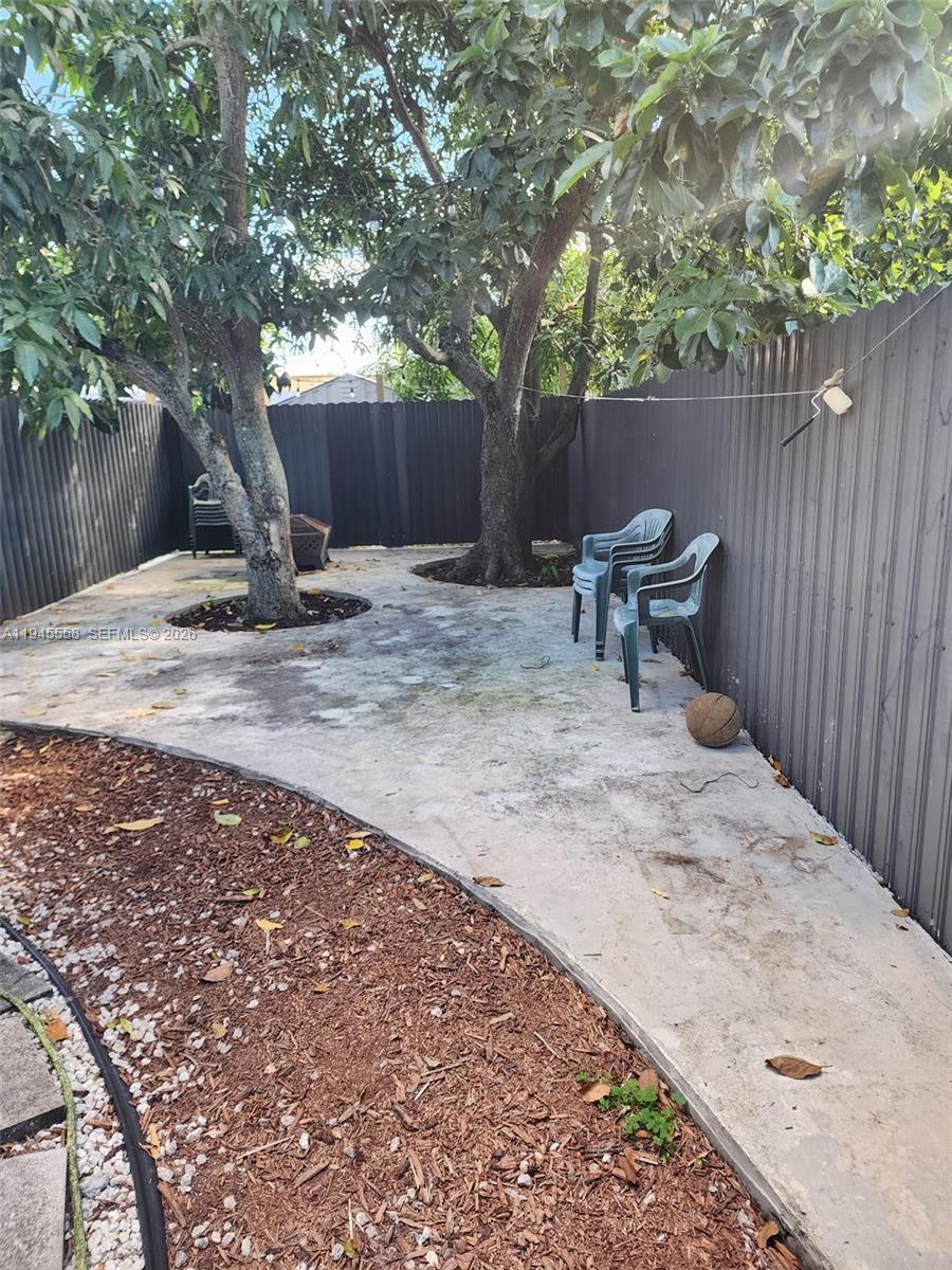 1360 Northeast 144th Street, Unit 3 Miami, FL 33161 - Photo 11 of 12 a view of a backyard with a barbeque and a large tree