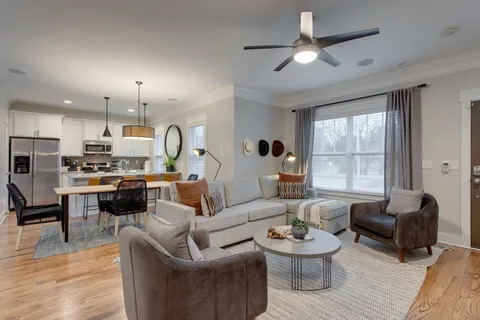 a living room with furniture kitchen view and a large window