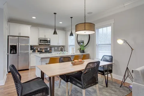 a kitchen with a dining table chairs stainless steel appliances and cabinets