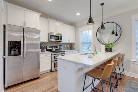 a kitchen with stainless steel appliances kitchen island a table chairs refrigerator and microwave