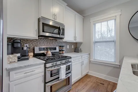 a kitchen with stainless steel appliances granite countertop a stove a microwave and a white cabinets