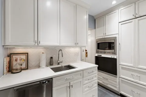 a kitchen with white cabinets and white appliances