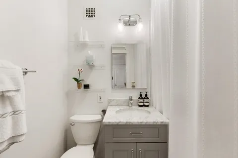 a bathroom with a granite countertop sink toilet and mirror