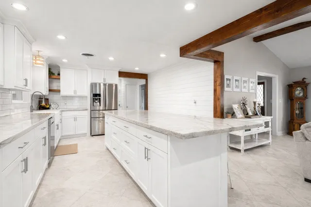 a large kitchen with stainless steel appliances kitchen island granite countertop a sink and cabinets