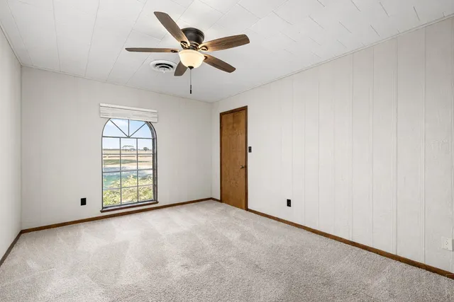 an empty room with windows and fan