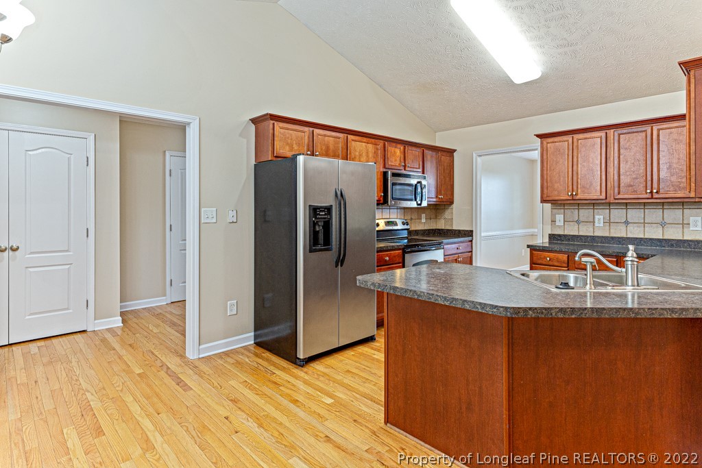 75 Hayden Lane Cameron, NC 28326 - Photo 10 of 35 a kitchen with stainless steel appliances granite countertop a refrigerator a stove and a sink with wooden floor