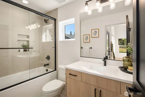 a bathroom with a sink a toilet a mirror and shower