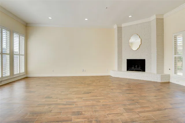 a view of an empty room with wooden floor and windows