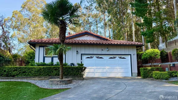 a front view of a house with a garden and tree