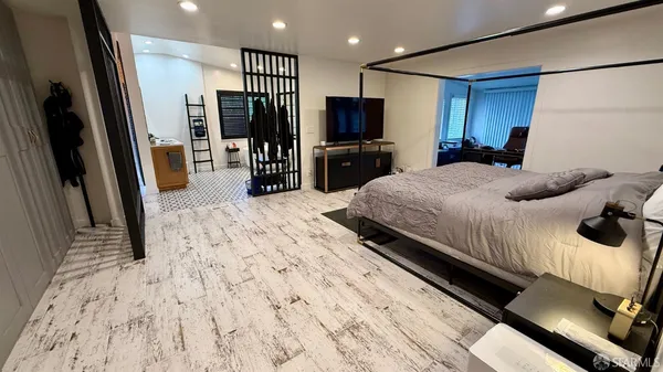 a bedroom with a bed window and a flat tv screen on the dresser