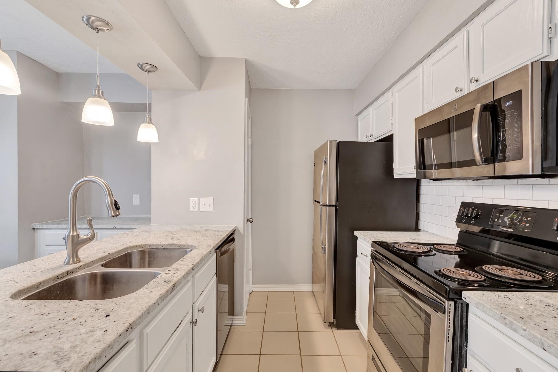 2402 Sycamore Avenue, Unit D4 Huntsville, TX 77340 - Photo 12 of 19 a kitchen with stainless steel appliances granite countertop a sink stove and refrigerator