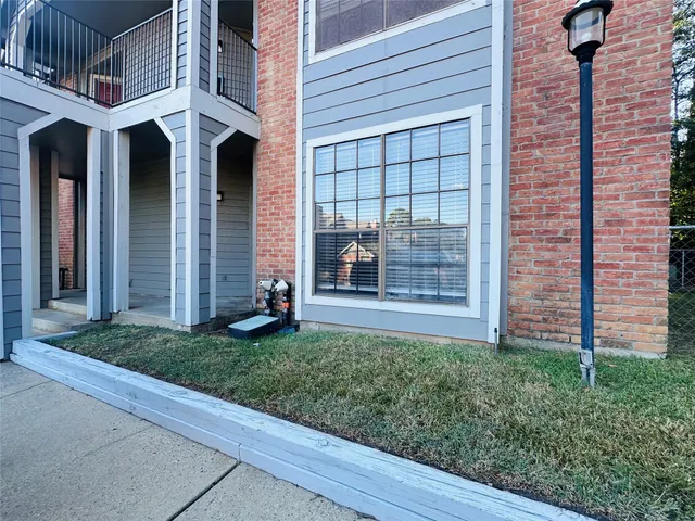 a view of a house with brick walls and a yard with plants