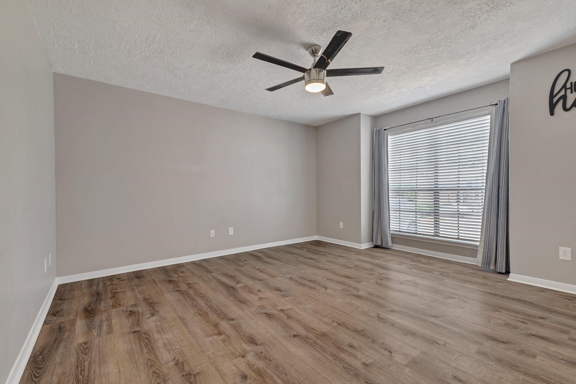 2402 Sycamore Avenue, Unit D4 Huntsville, TX 77340 - Photo 6 of 19 an empty room with wooden floor fan and windows