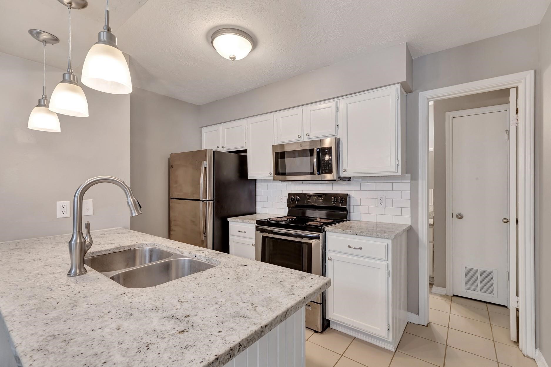 2402 Sycamore Avenue, Unit D4 Huntsville, TX 77340 - Photo 10 of 19 a kitchen with stainless steel appliances granite countertop a sink stove and refrigerator