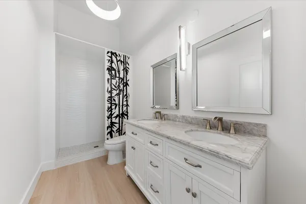 a bathroom with a granite countertop sink a toilet a mirror and shower