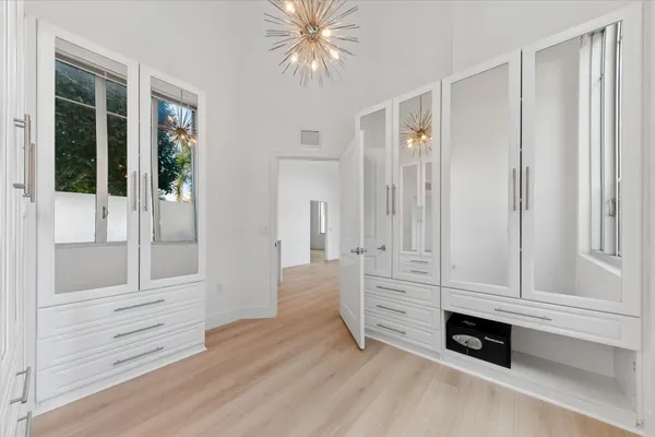 an empty room with wooden floor cabinet and windows