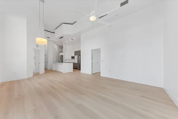 an empty room with a kitchen and a chandelier fan
