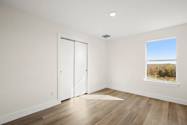 an empty room with wooden floor and windows