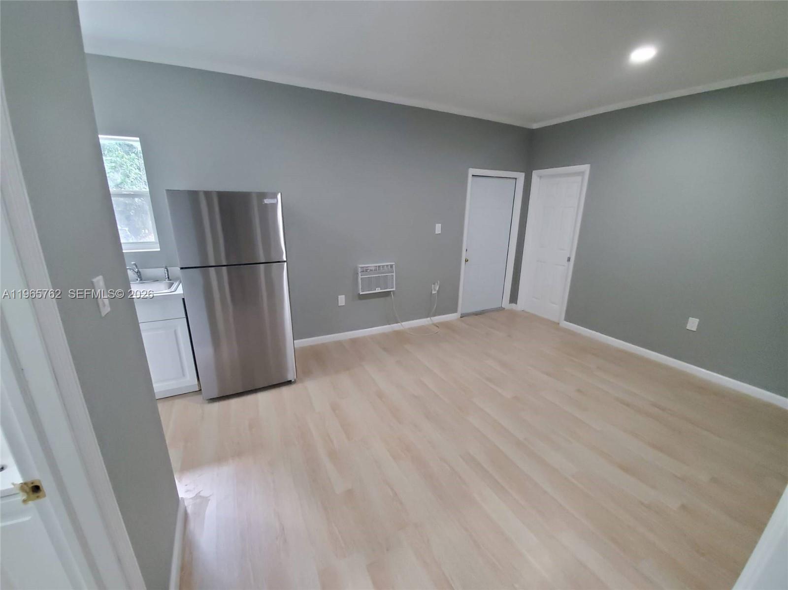 2425 Northwest 28th Street Miami, FL 33142 - Photo 12 of 18 a view of kitchen with refrigerator and wooden floor