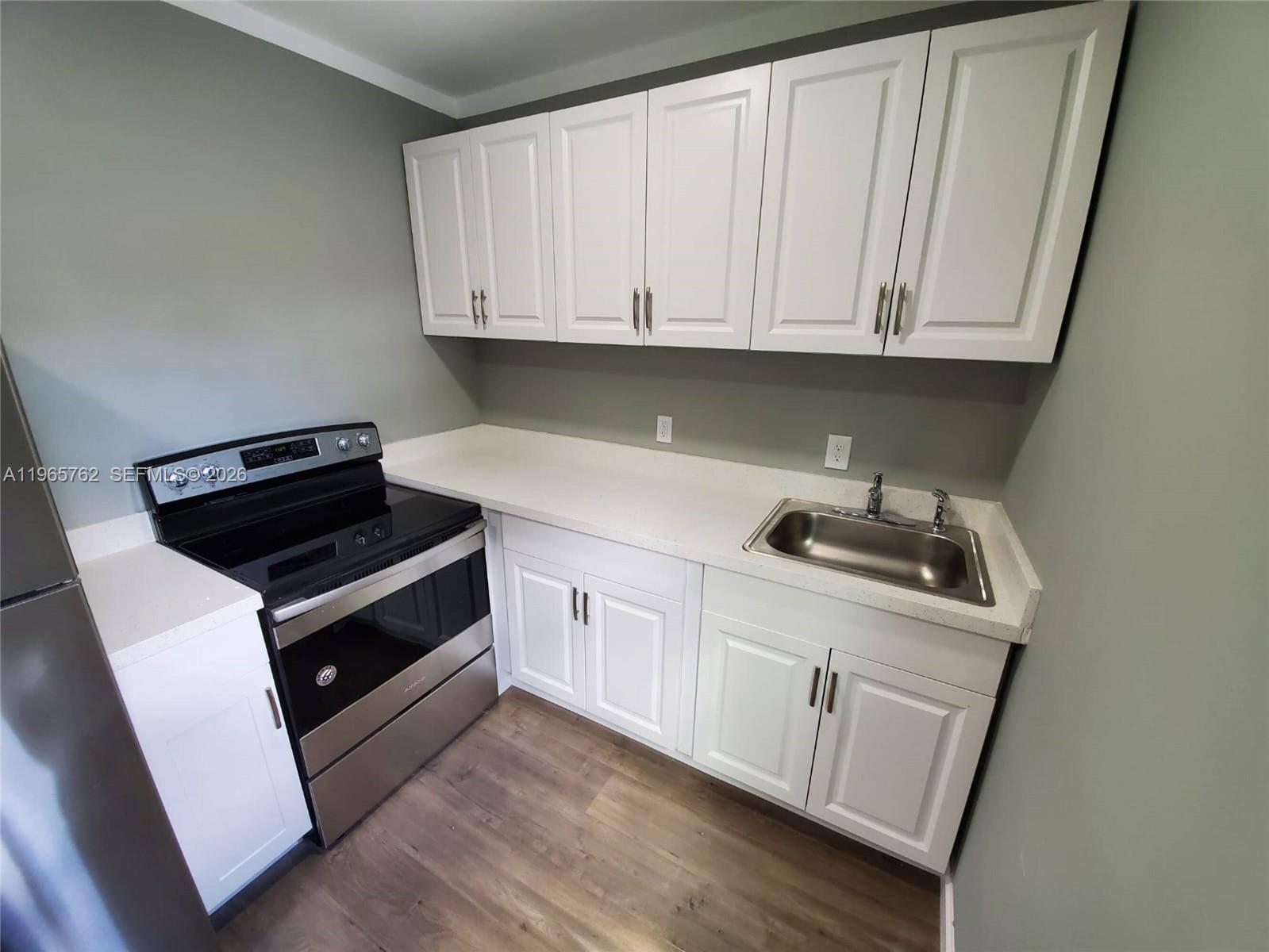 2425 Northwest 28th Street Miami, FL 33142 - Photo 8 of 18 a kitchen with white cabinets and white appliances