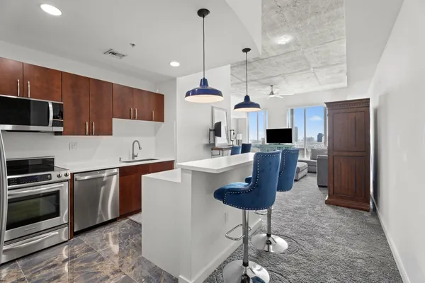 a kitchen with stainless steel appliances granite countertop a sink a stove a refrigerator cabinets and chairs