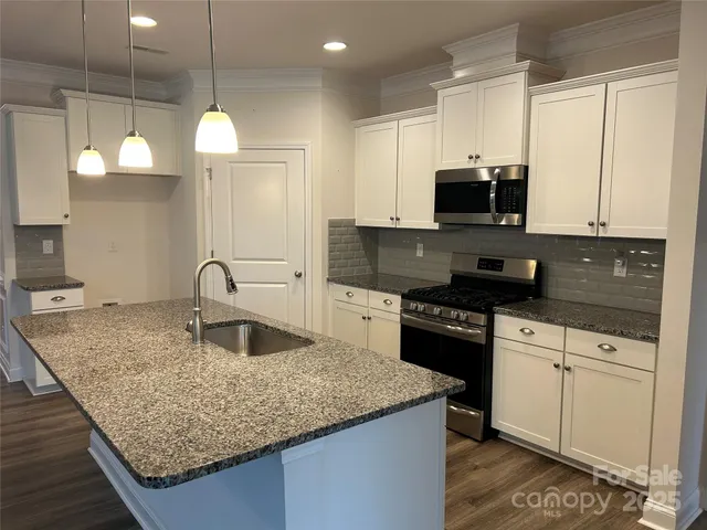 a kitchen with stainless steel appliances granite countertop a sink a stove and a microwave