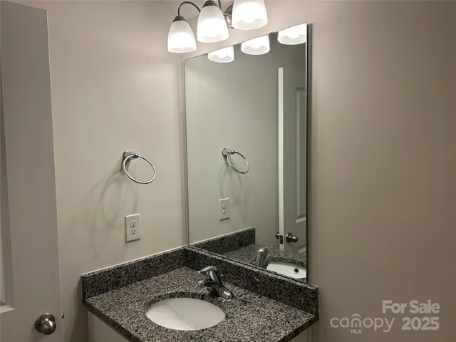 a bathroom with a granite countertop sink a mirror and shower