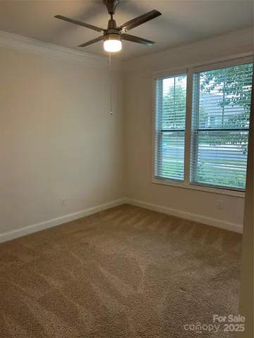 en empty room with windows and ceiling fan
