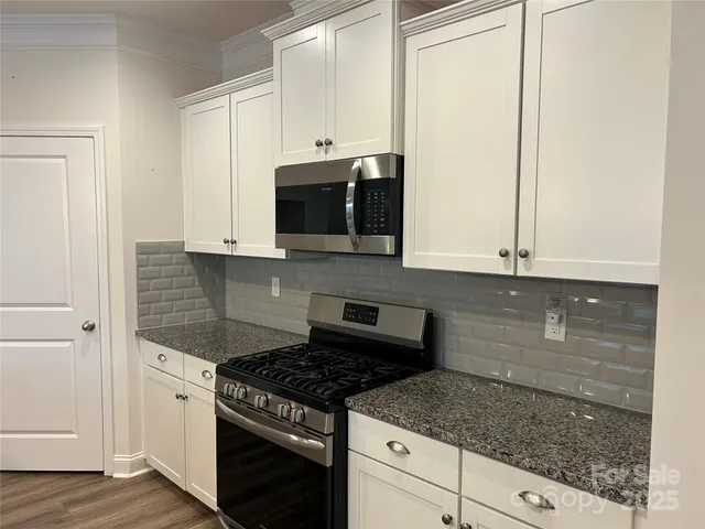 a kitchen with granite countertop white cabinets and stainless steel appliances