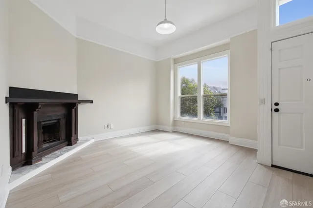 an empty room with wooden floor fireplace and windows