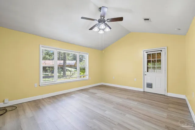 a view of an empty room with a window and wooden floor