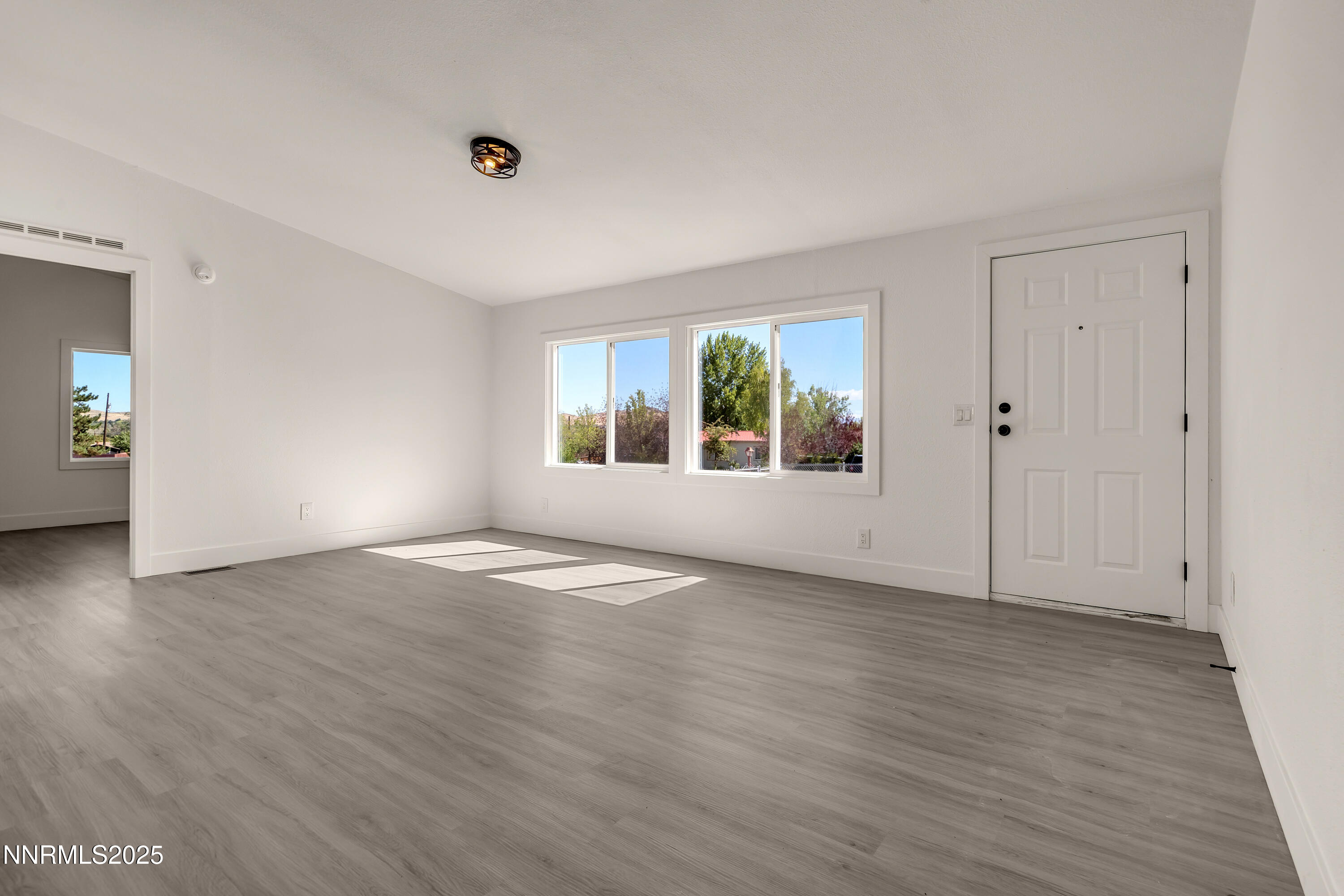 145 Wewoka Way Sun Valley, NV 89433 - Photo 7 of 36 an empty room with wooden floor and windows