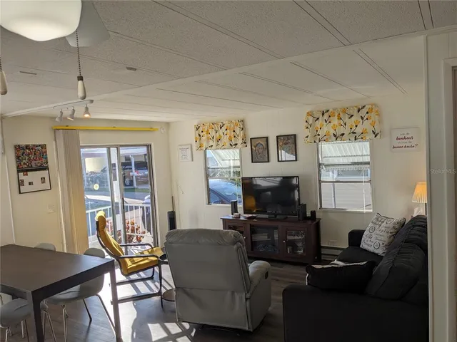 a living room with furniture a flat screen tv and a window
