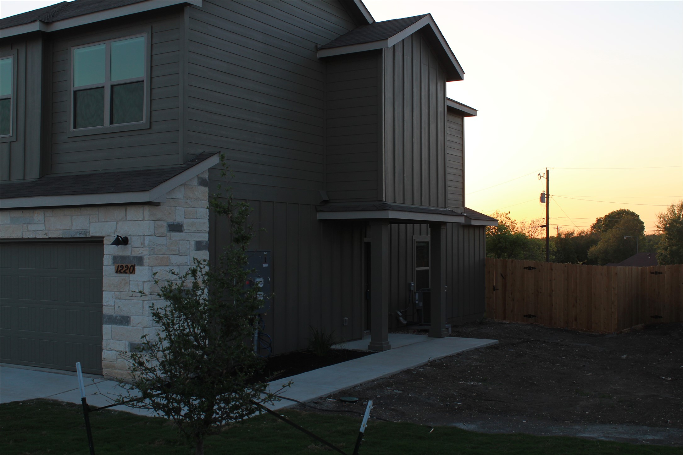 View of side of home featuring board and batten siding, an attached garage, driveway, and stone siding