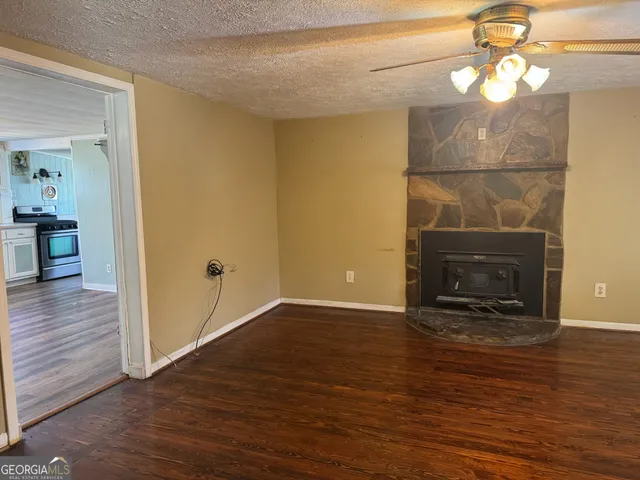 a view of an empty room with wooden floor and a fireplace