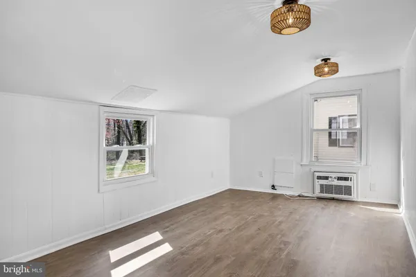 an empty room with windows and way to kitchen
